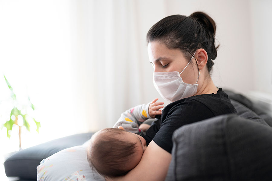 Madre con cubrebocas amamantando a su bebé